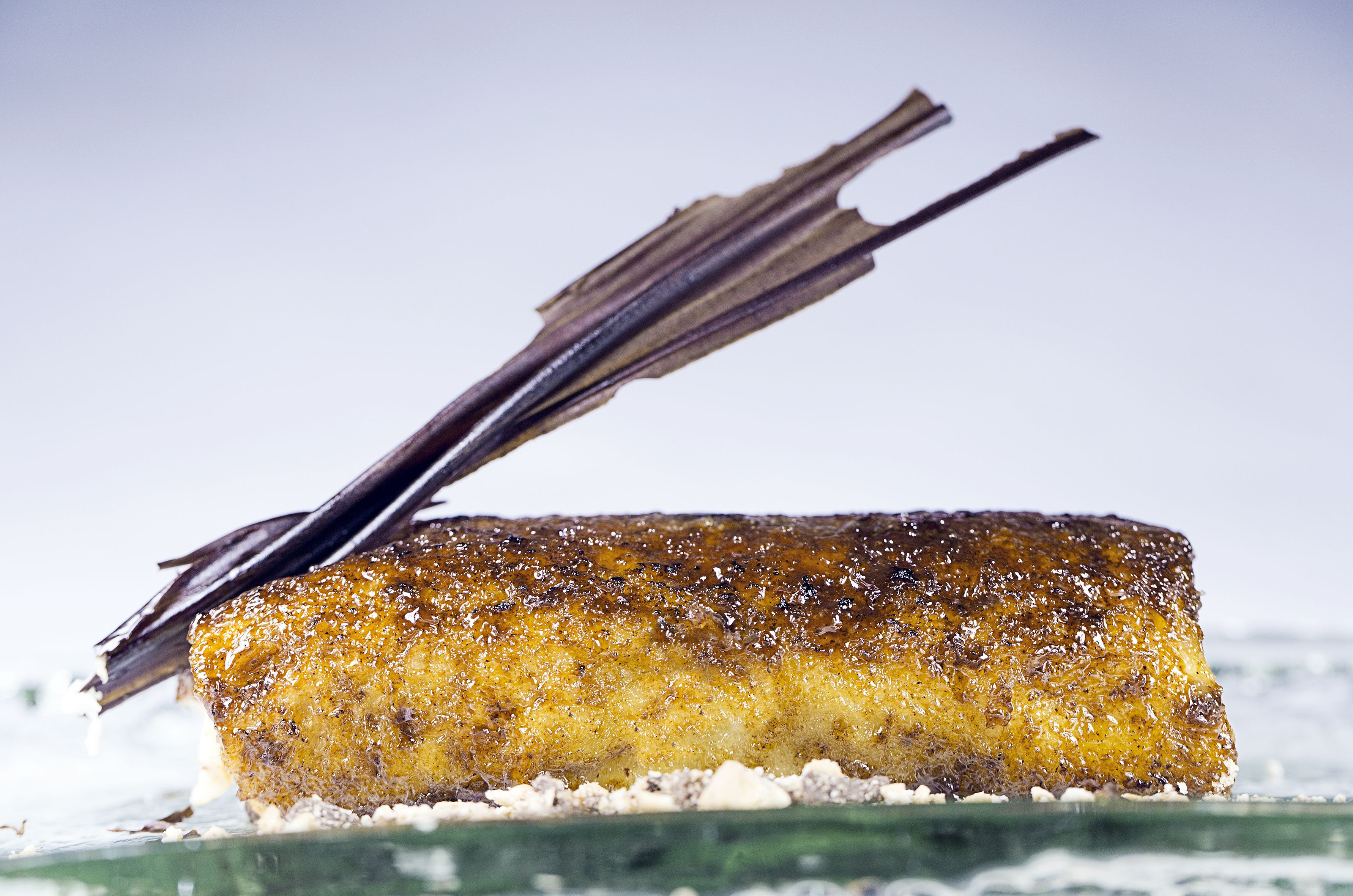 A dessert with a golden-brown crust, a dark garnish on top, and a white base.