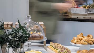 Un bufé con diversas opciones de comida, incluyendo pasteles, frutas y postres.