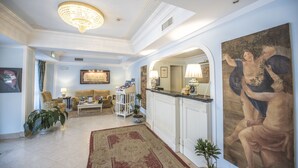 A spacious living room with a chandelier, a large painting, and a dining area with a bar. - Hotel Villa Daphne (Giardini Naxos)