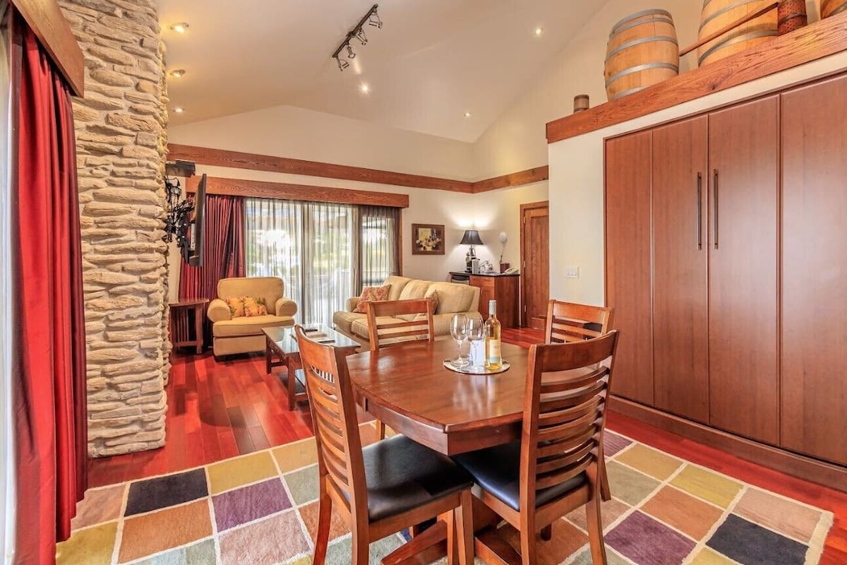 A dining area with a wooden table and chairs, a stone accent wall, and a large wooden cabinet.