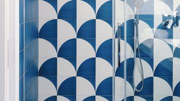 Una doccia con un motivo a piastrelle geometriche e un soffione a mano.