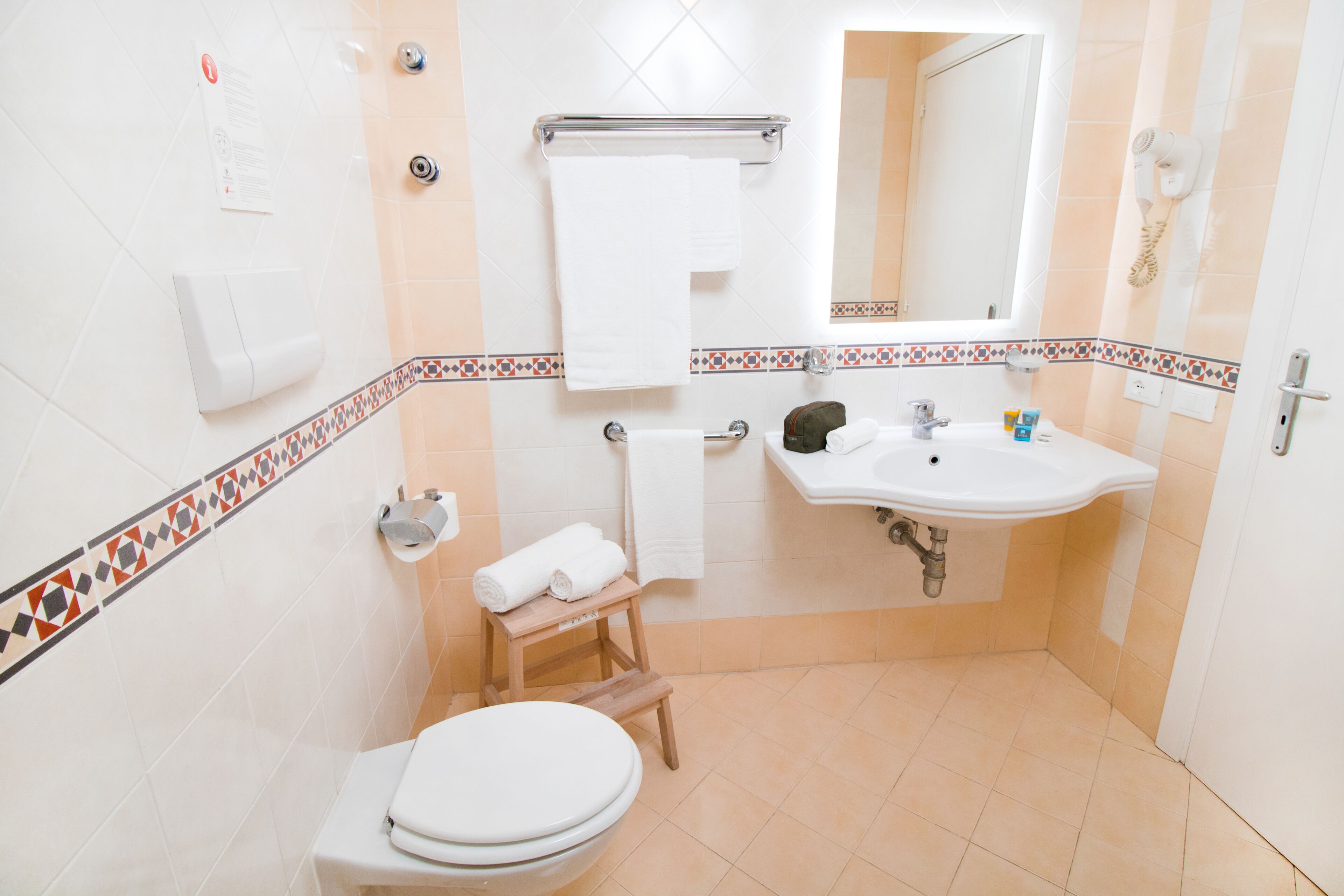 A bathroom with a toilet, sink, and a small wooden stool.