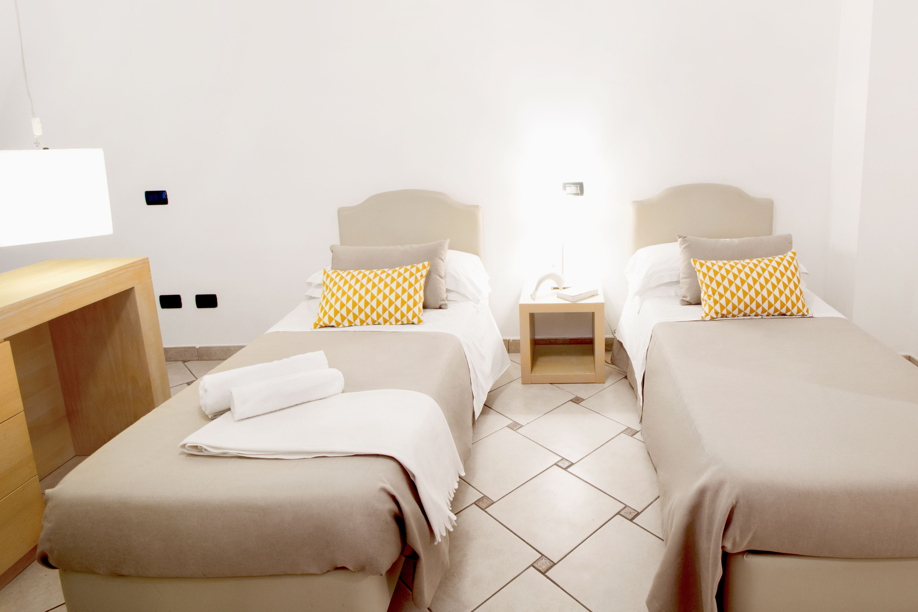 A hotel room with two beds, a wooden desk, and a nightstand.