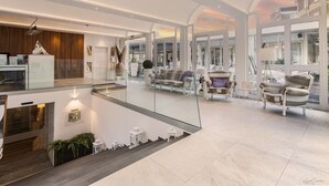 A spacious, modern interior with a high ceiling, glass railings, and a view of the outside.