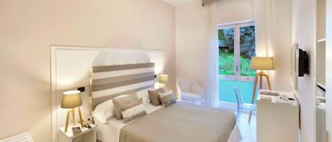 A bedroom with a bed, bedside tables, a chair, a TV, and a window with curtains.