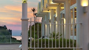 A hotel entrance with a gated driveway, a sign reading "HOTEL", and a modern architectural design with arched windows.