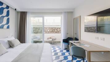 A hotel room with a bed, a desk, a chair, a large window, and a view of the outside.