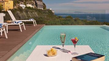 Area piscina con sedie a sdraio, un libro, snack e bevande.