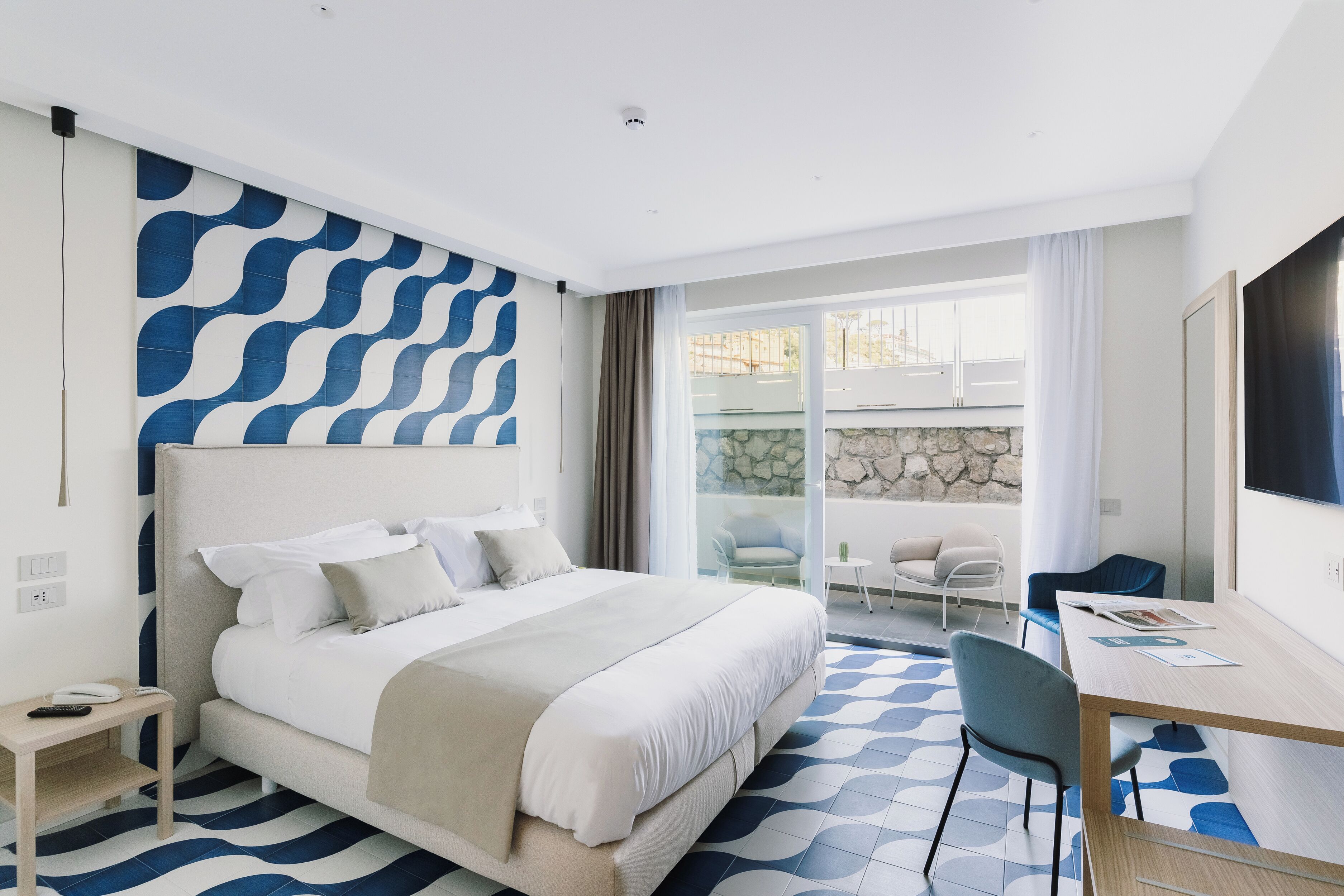Une chambre d’hôtel moderne dotée d’un grand lit, d’un bureau et d’un balcon aménagé avec des sièges.