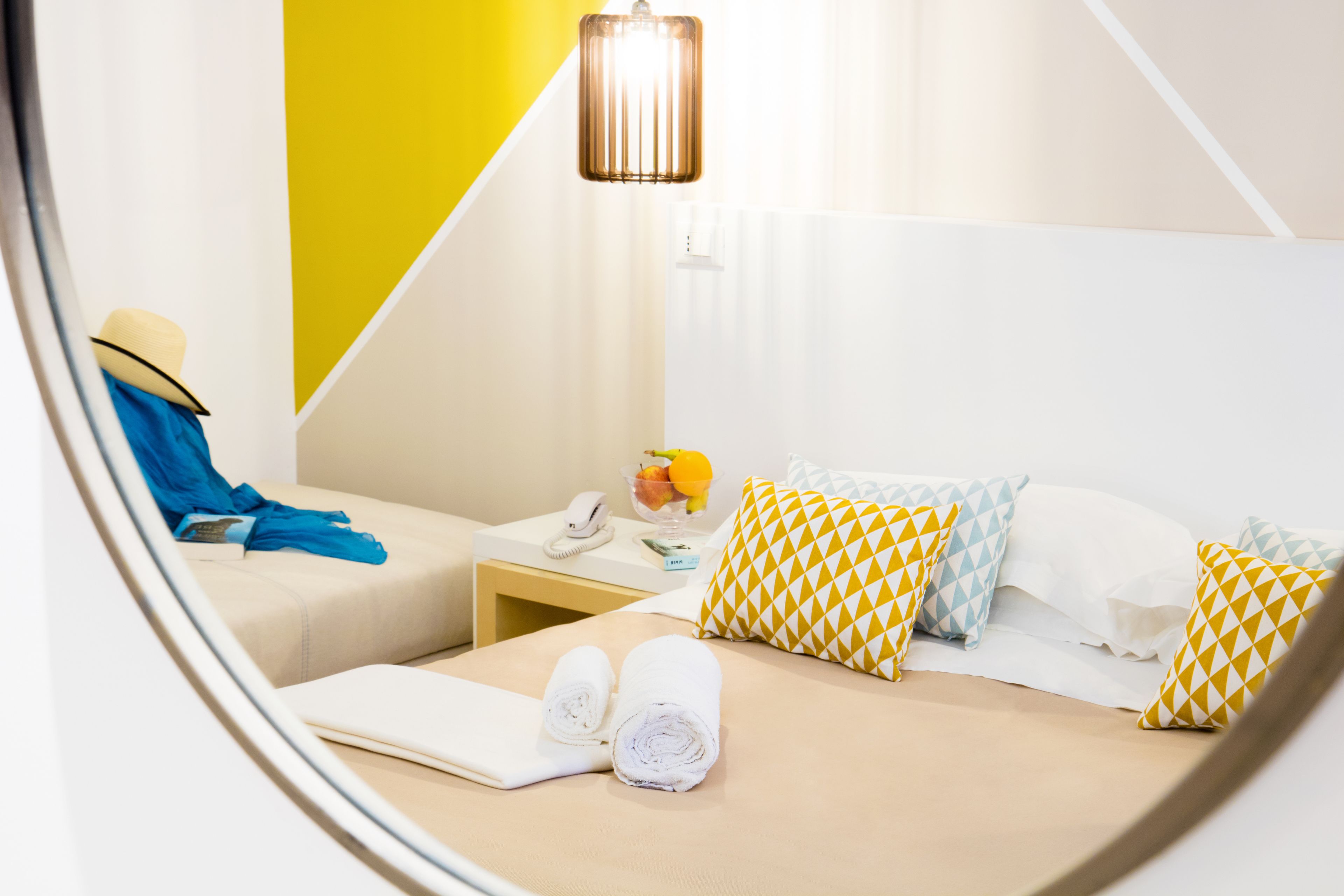 Quarto de hotel com cama, mesa de cabeceira, abajur e janela.