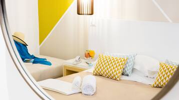 Una habitación de hotel con una cama, una mesita de noche, una lámpara y una ventana.