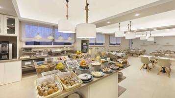 Un buffet de petit-déjeuner moderne proposant une variété de plats et un espace repas avec des tables et des chaises.