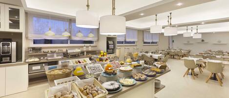 A modern breakfast buffet with various food items and a seating area with tables and chairs.