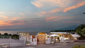 A hotel with a white facade, arched entrance, and a view of the sea.