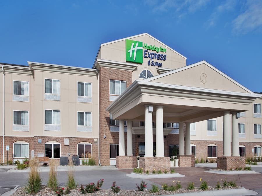 Een Holiday Inn Express & Suites hotel met een overdekte ingang en meerdere ramen.