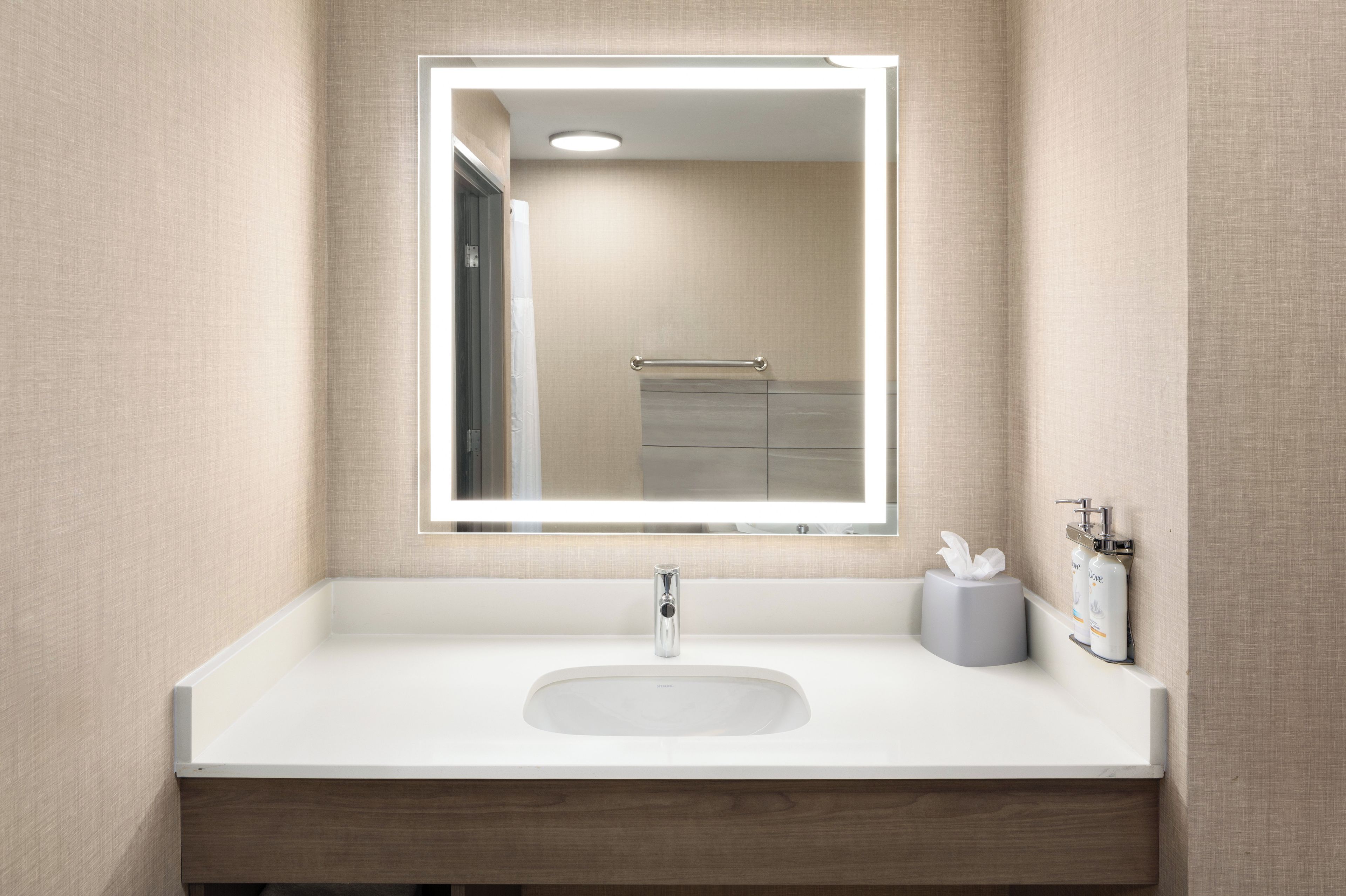 Une salle de bain moderne avec un lavabo blanc, un miroir et un distributeur de serviettes.