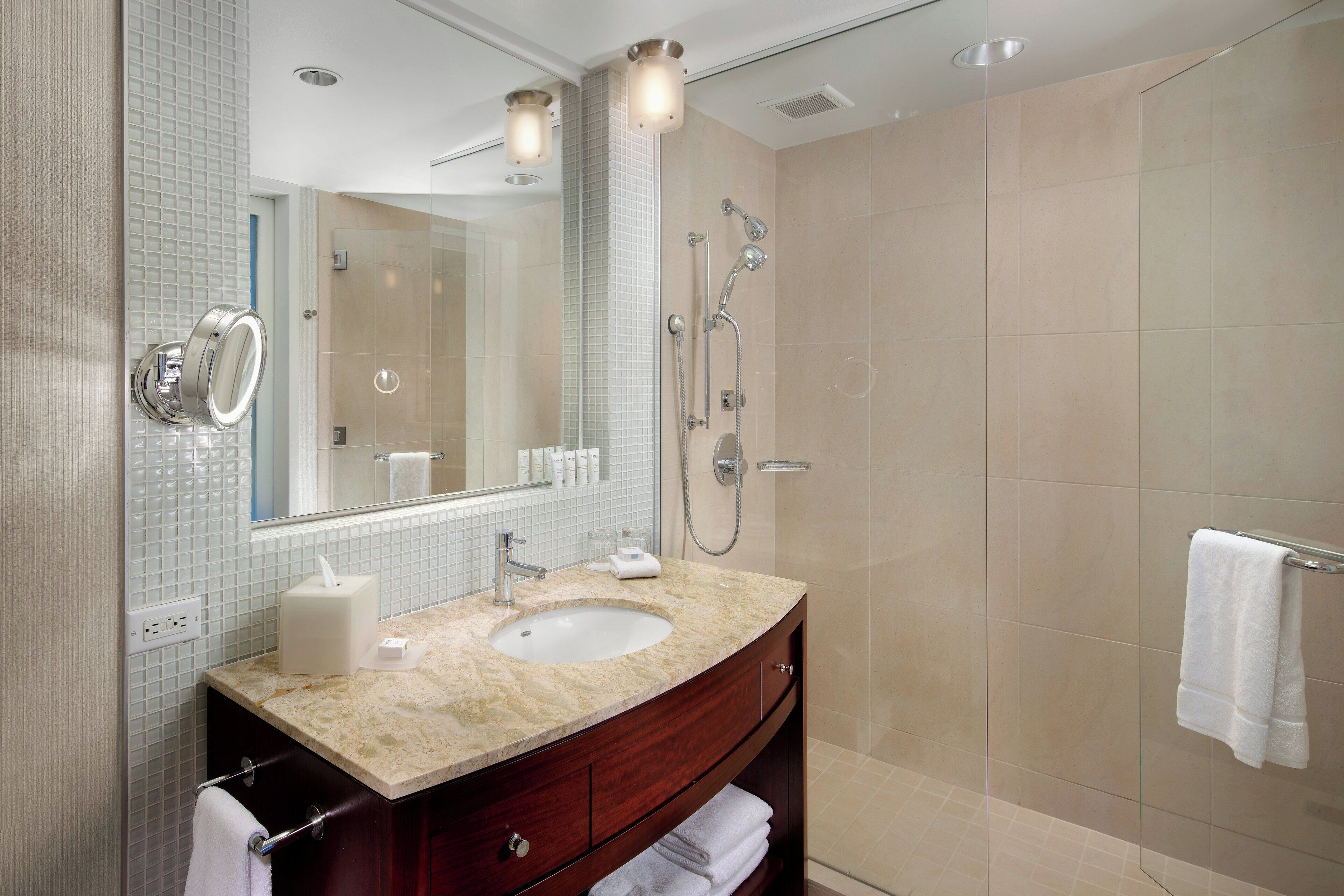Une salle de bain moderne avec un lavabo en marbre, un grand miroir et une douche à parois de verre.
