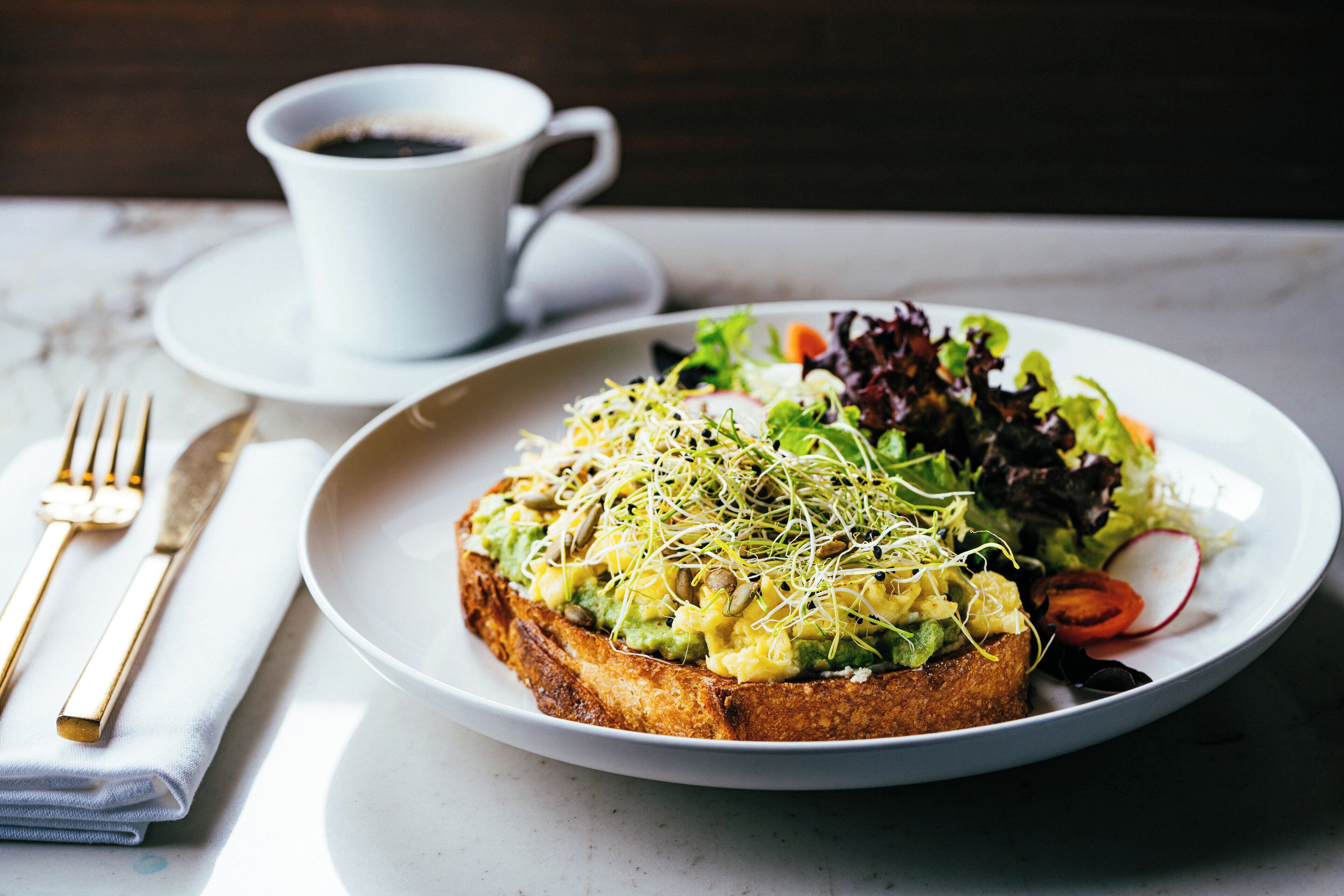 A plate of food with a cup of coffee on a table.