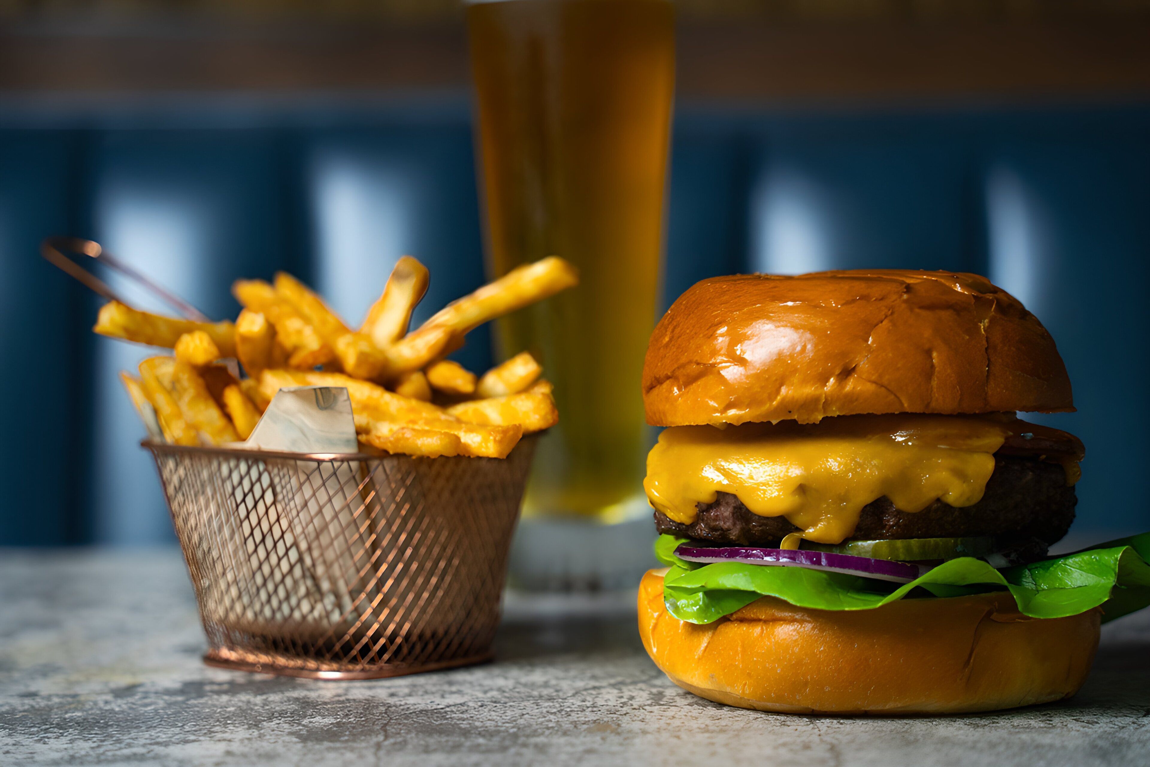 A burger and a basket of fries on a table.