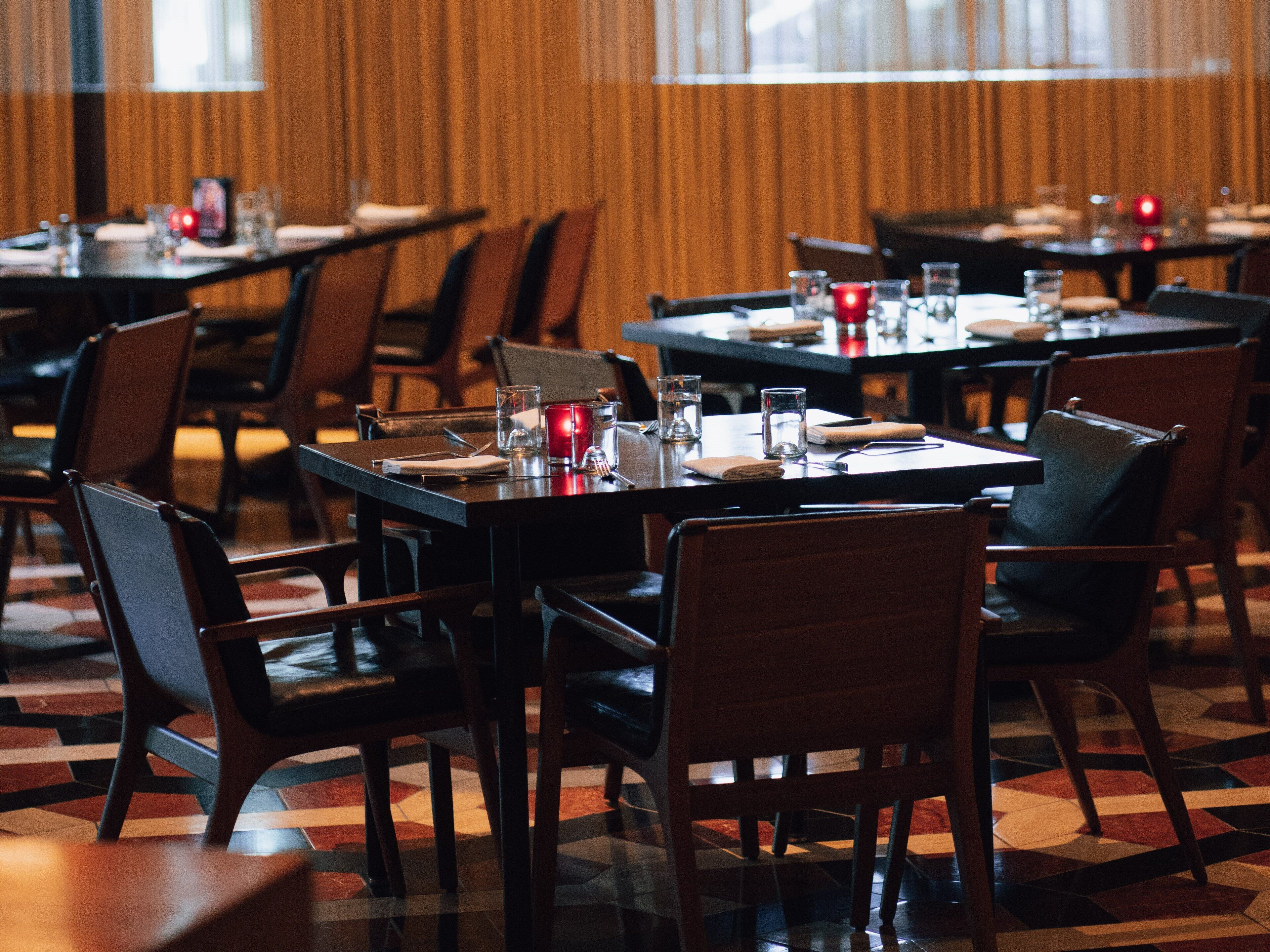 A restaurant with tables set for dining, chairs, and a patterned floor.