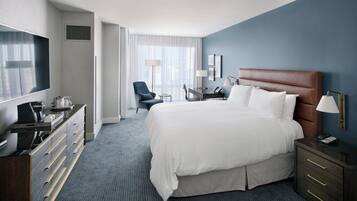 Ein Hotelzimmer mit einem großen Bett, einem Schreibtisch, einem Sessel, einem Fernseher und einer Kommode.