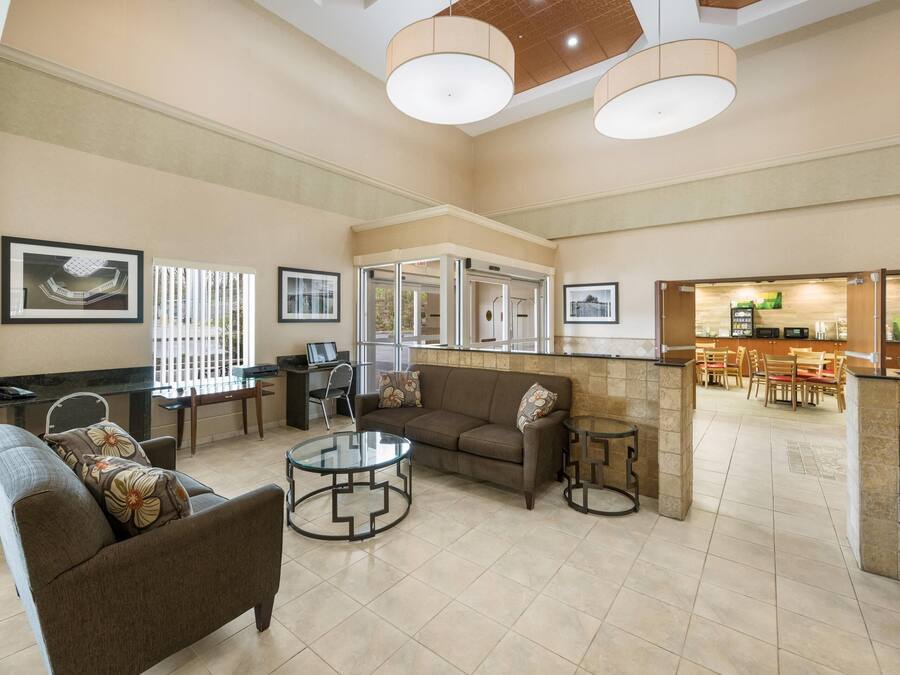 A spacious lobby with a sofa, two round tables, a coffee station, and framed artwork on the walls.