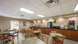 A restaurant with multiple tables and chairs, a kitchen area, and a microwave.