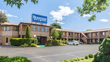 Guests can enjoy a convenient stay at this hotel, featuring a two-story building with a flat roof and a green entrance area.