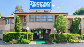 A Rodeway Inn & Suites building with a sign, a green entrance mat, and well-maintained hedges. - Rodeway Inn & Suites Branford - Guilford (Branford)