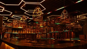 Un bar con lámparas hexagonales y estantes llenos de botellas.