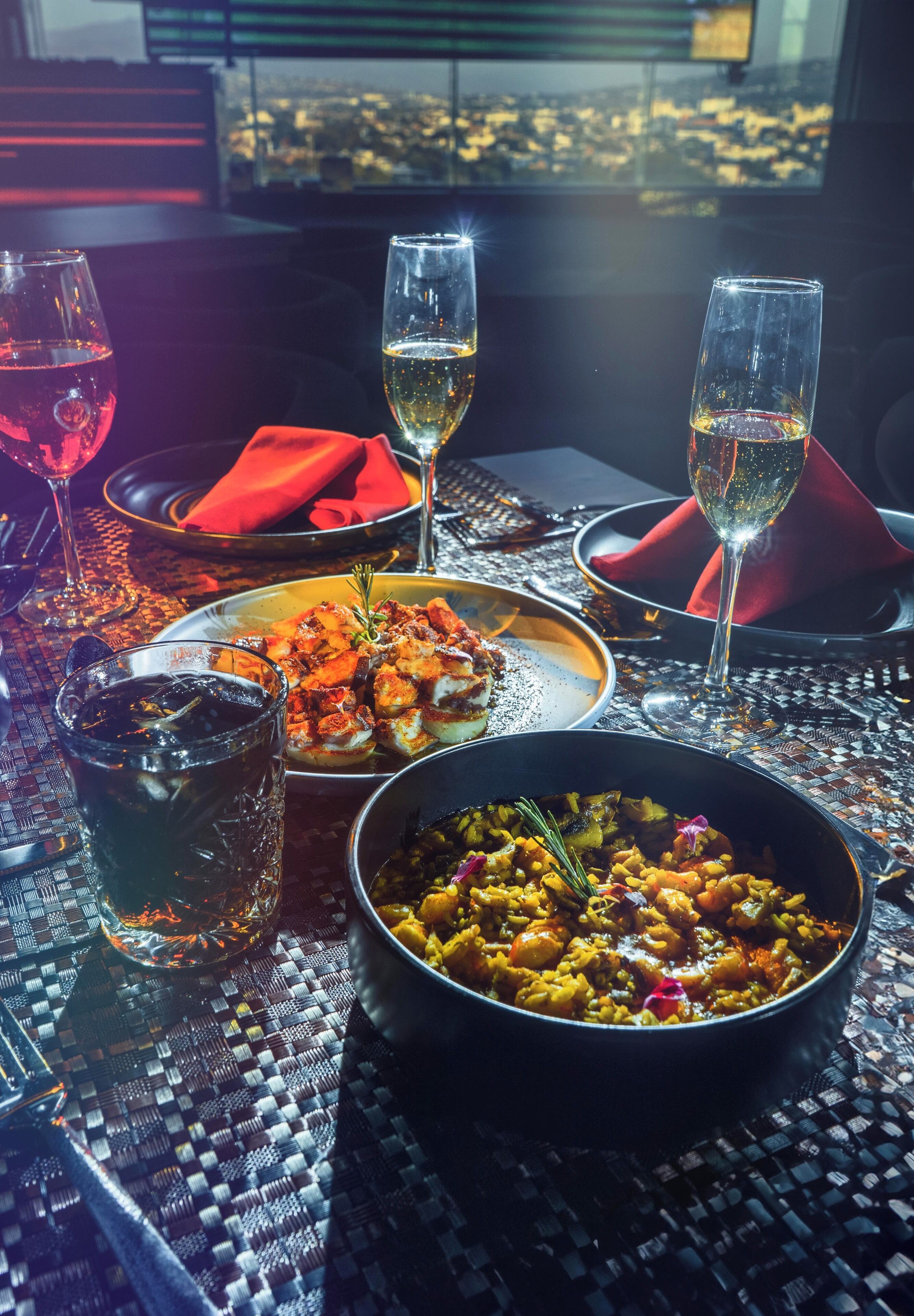 Une table dressée avec un bol de riz, deux verres de vin et une assiette de nourriture.