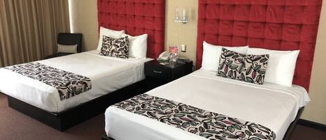 Dos camas dobles con cabeceros rojos, ropa de cama blanca y almohadones estampados.