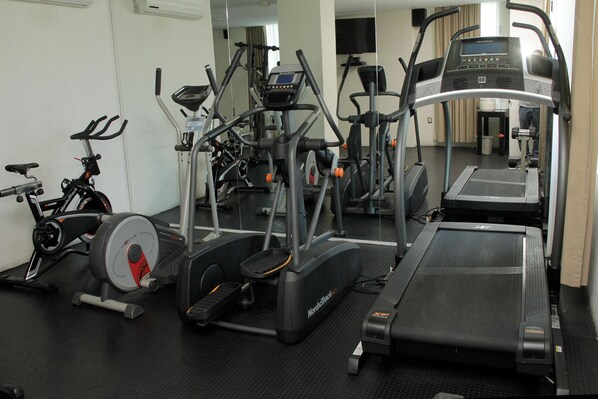 Un gimnasio con diverso equipo de ejercicio, incluyendo cintas de correr, una bicicleta estática y máquinas de pesas.