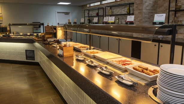 A buffet counter with various food items and serving utensils.