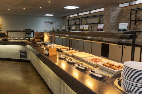 A buffet setup with various food items and serving utensils.