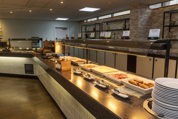 A buffet counter with various food items and serving utensils.