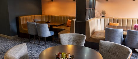 A modern lounge area with a round table, cushioned seating, and a small plant.