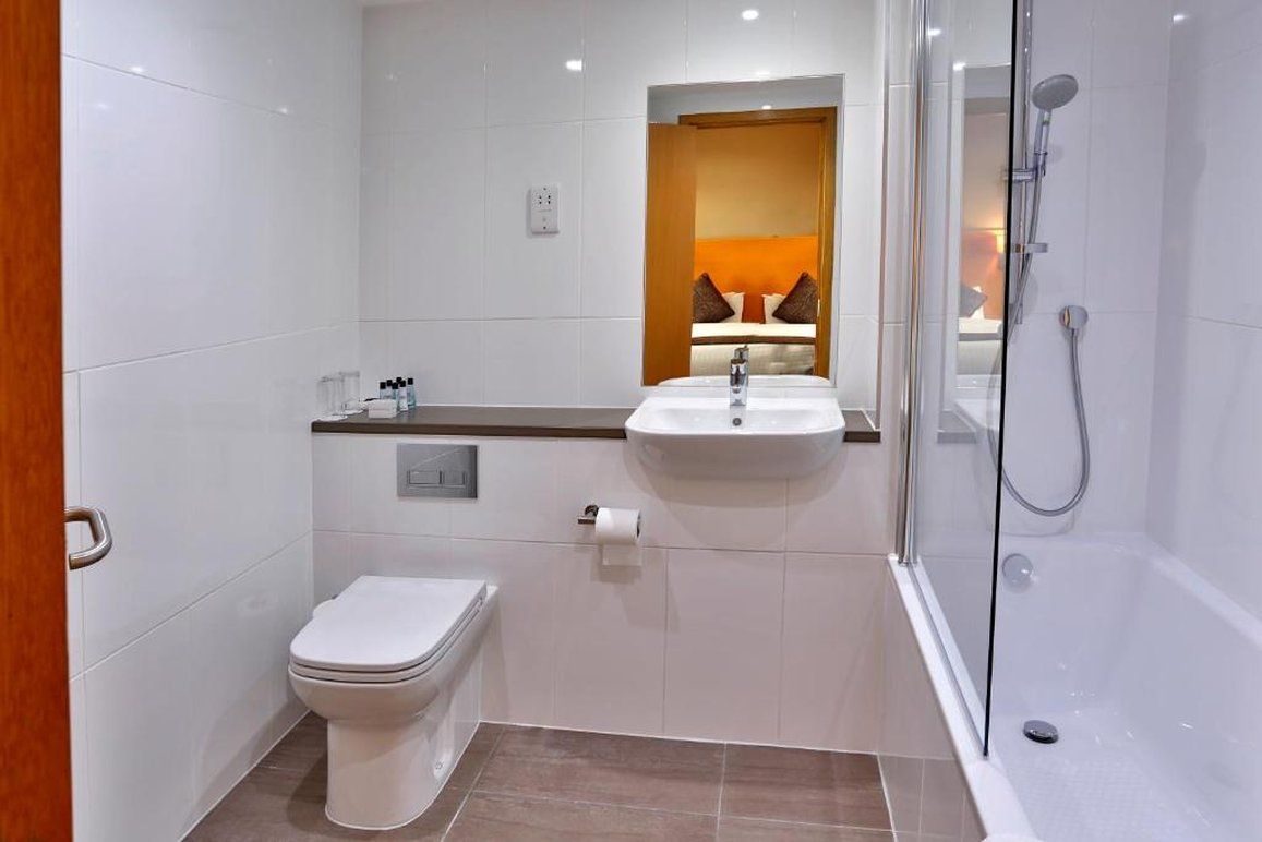 A modern bathroom with a toilet, sink, and shower.