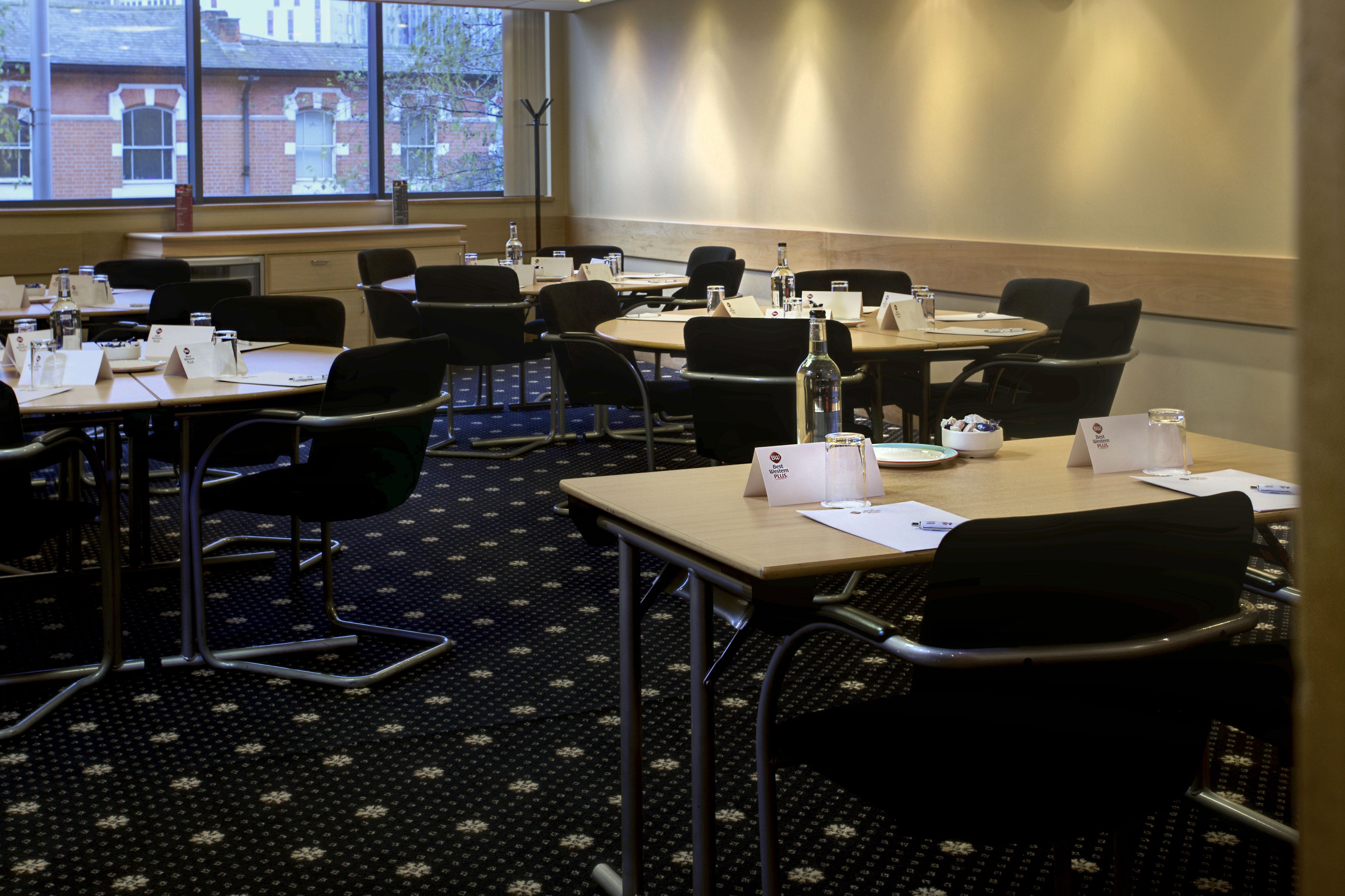 A conference room with multiple tables and chairs, equipped with nameplates, water bottles, and notepads.