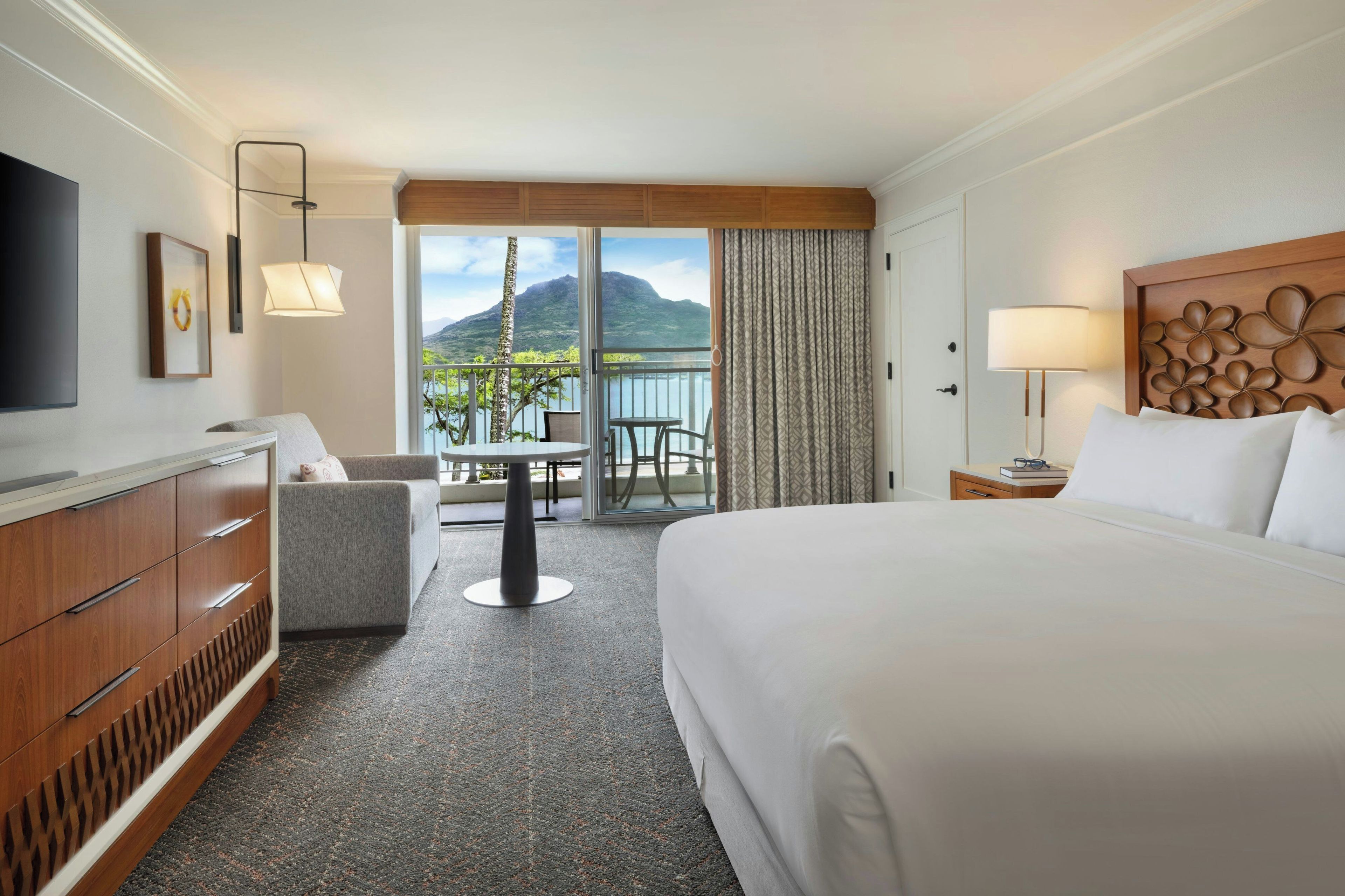 Une chambre d’hôtel comprenant un lit, un bureau, une chaise, une télévision et un balcon avec vue sur la montagne.