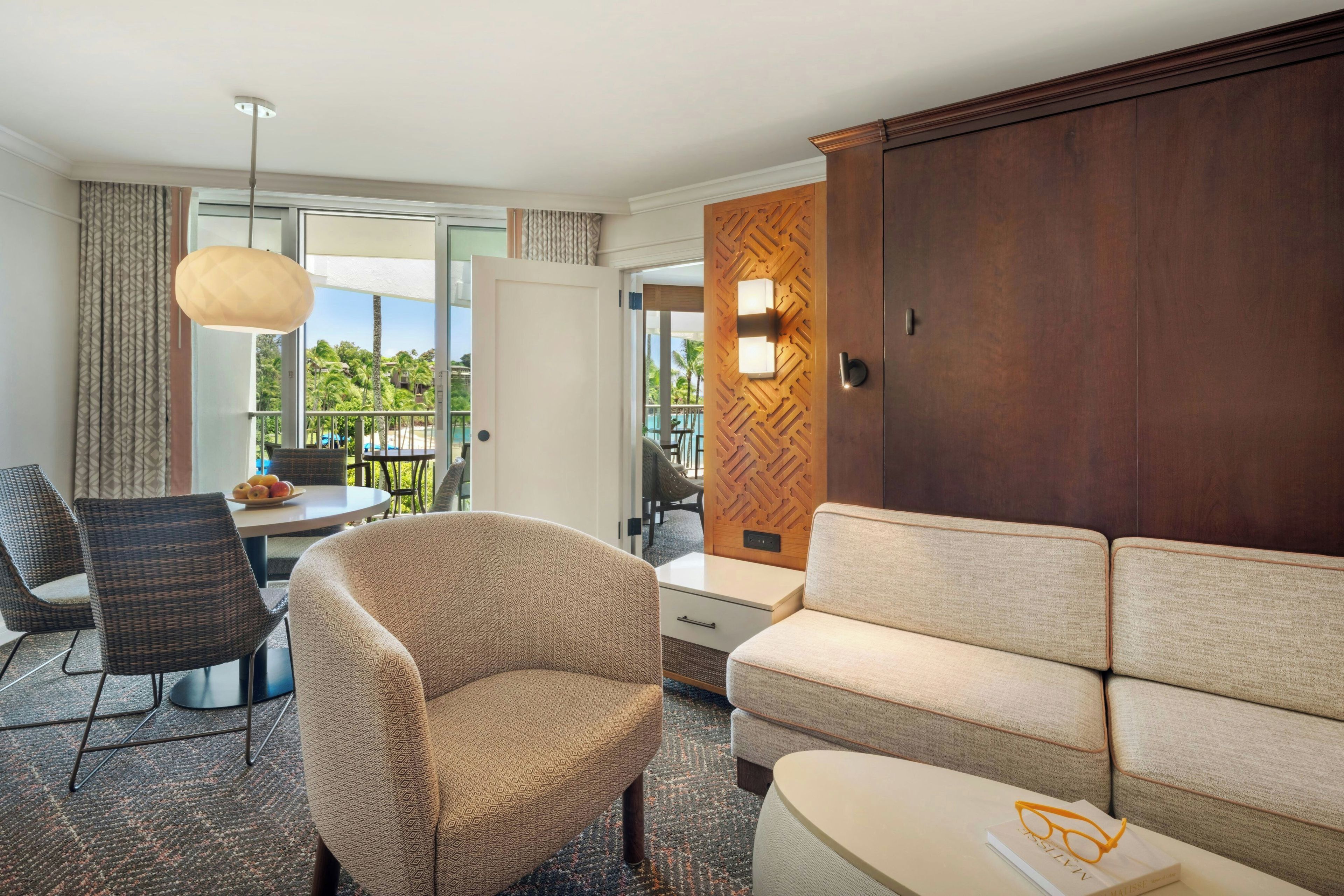 Une chambre d’hôtel équipée d’un canapé, d’un fauteuil, d’une table à manger et offrant une vue sur l’extérieur.