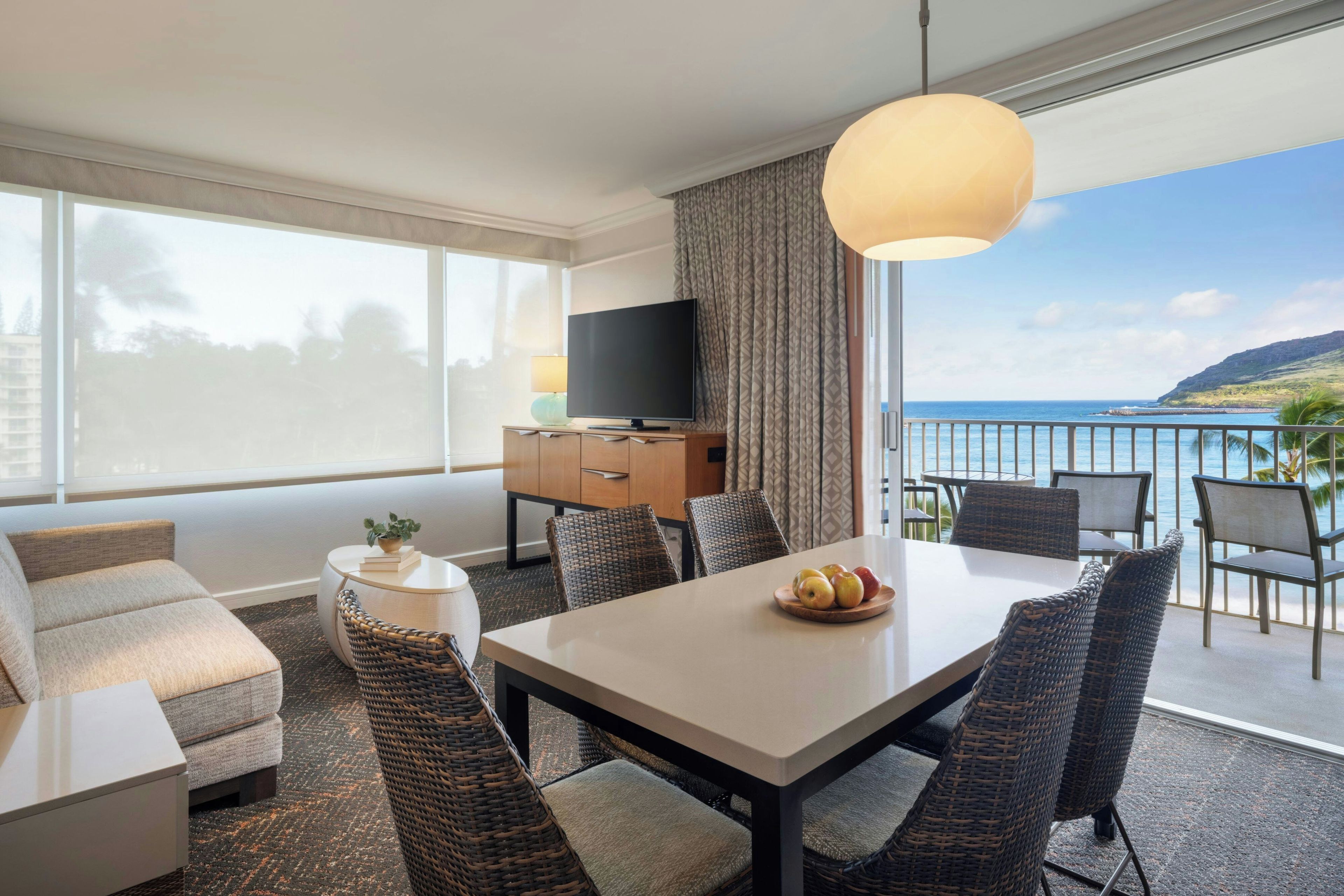 Una habitación de hotel moderna con balcón, una mesa de comedor y un sofá.