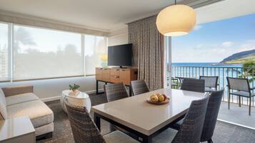 Una habitación de hotel moderna con balcón, una mesa de comedor y un sofá.