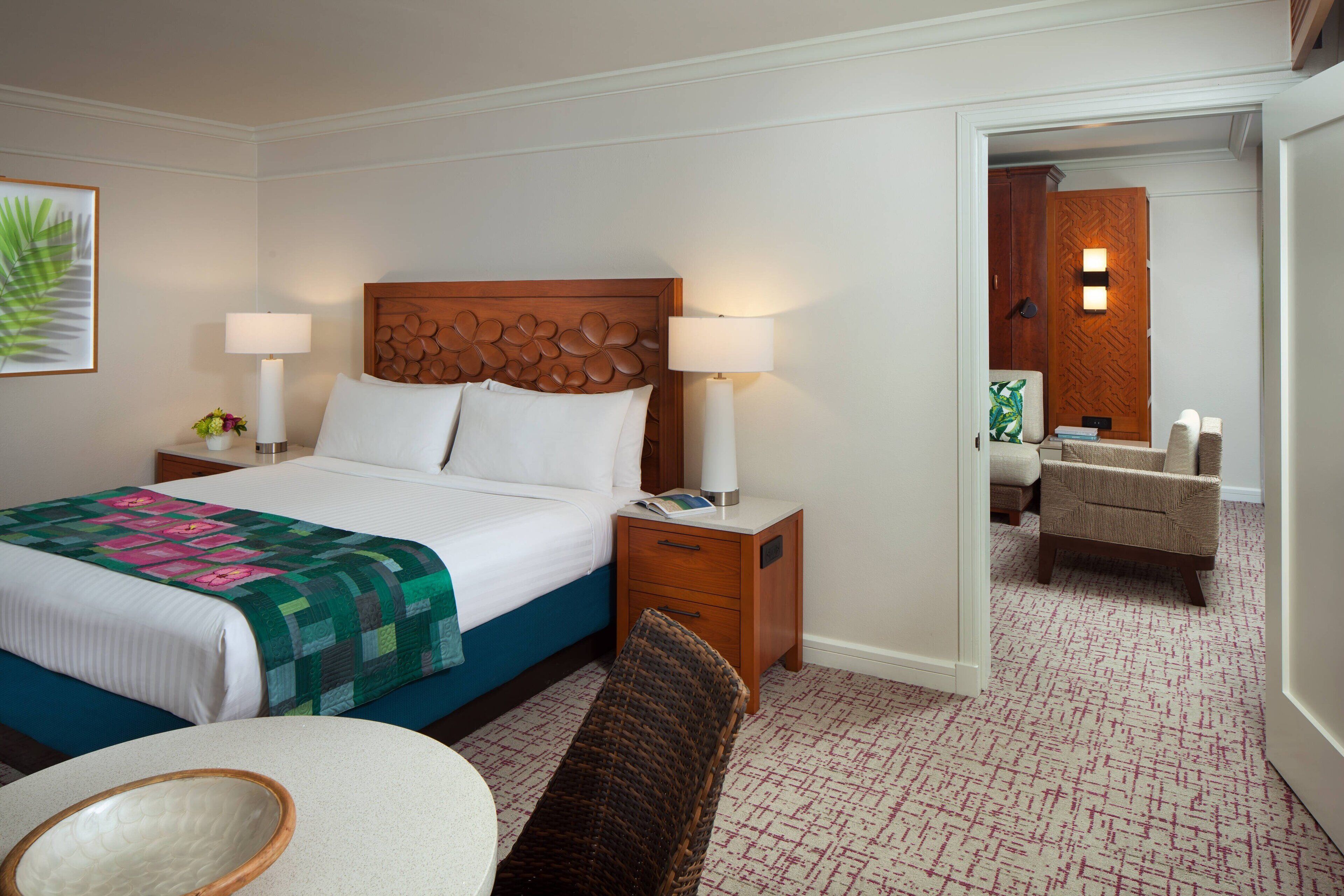 Une chambre d’hôtel comprenant un lit, des tables de chevet, une chaise, une petite table et un miroir.