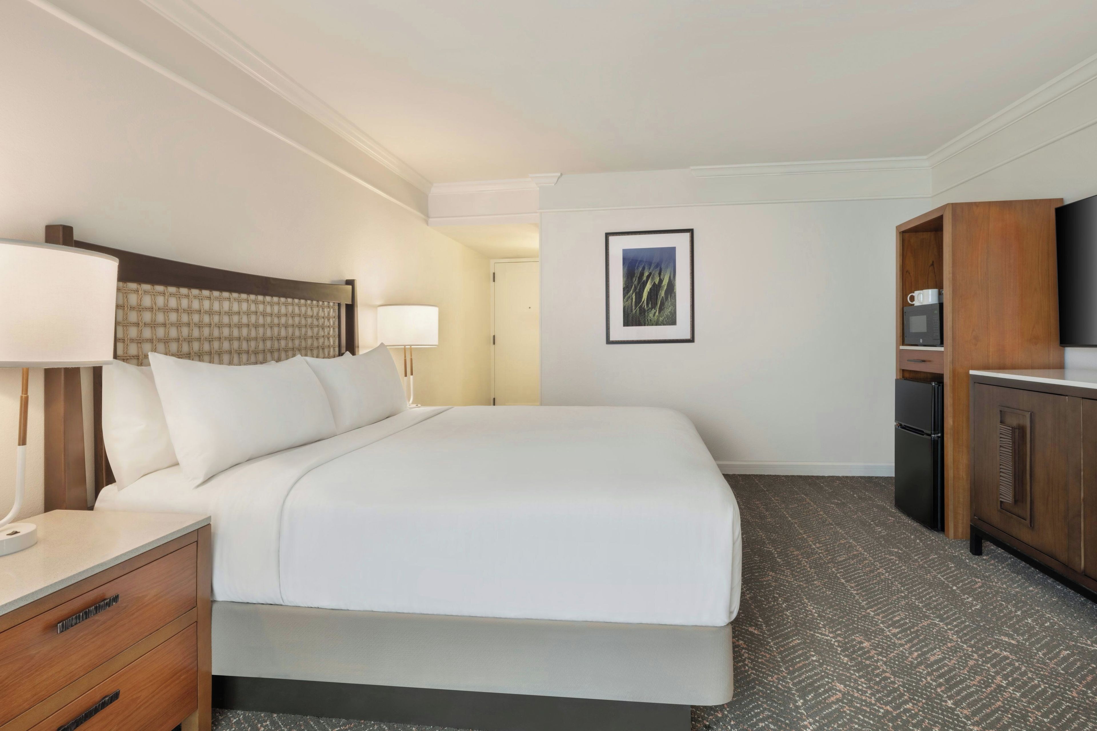 Una habitación de hotel con cama, mesitas de noche, escritorio, televisor y armario.