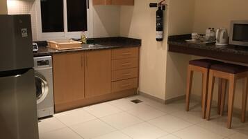 A compact kitchen with a washing machine, a coffee maker, and a CO2 fire extinguisher.