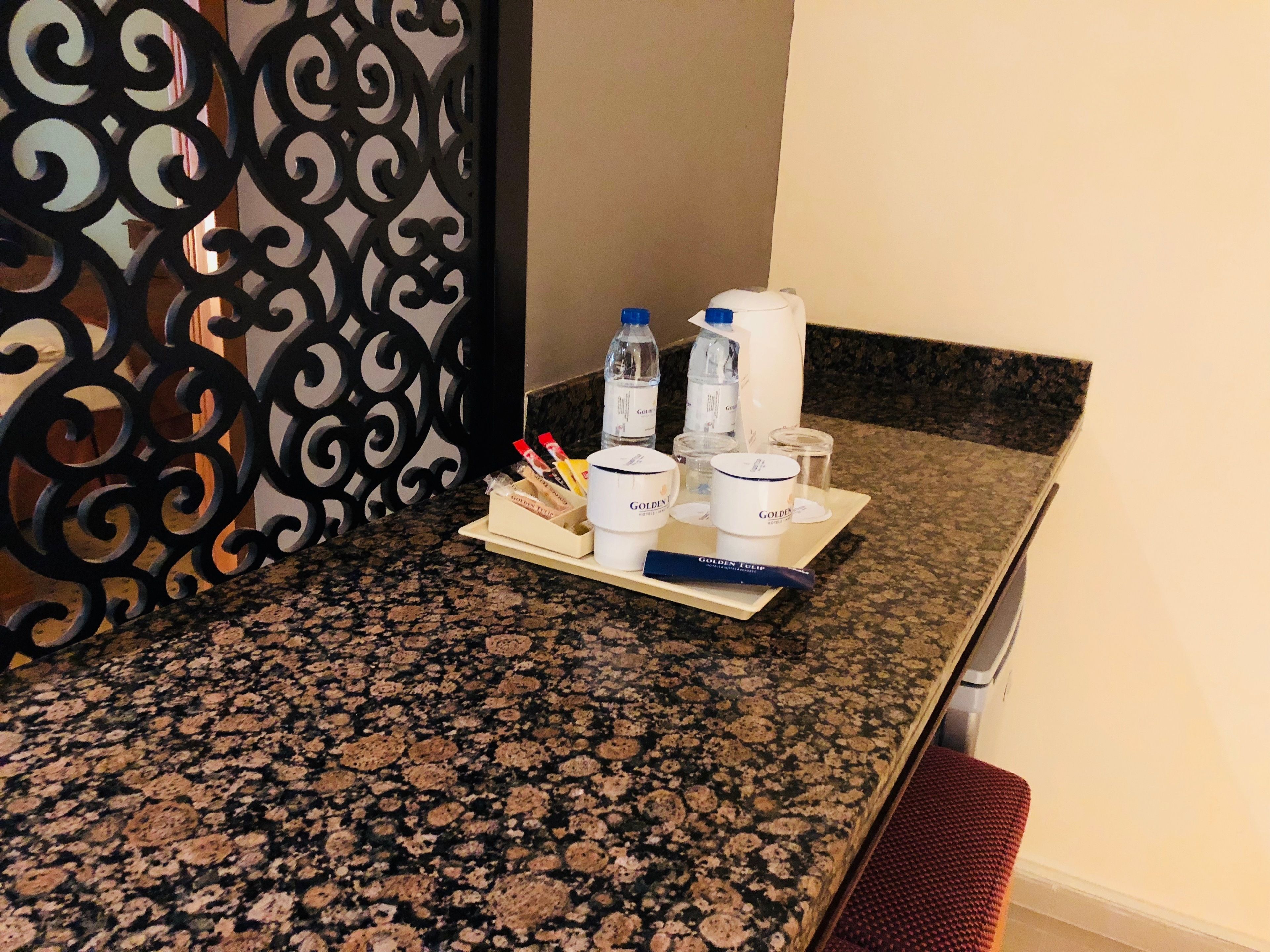 A kitchen counter with a granite surface, a tray with a water bottle, a coffee maker, and a container of coffee creamer.