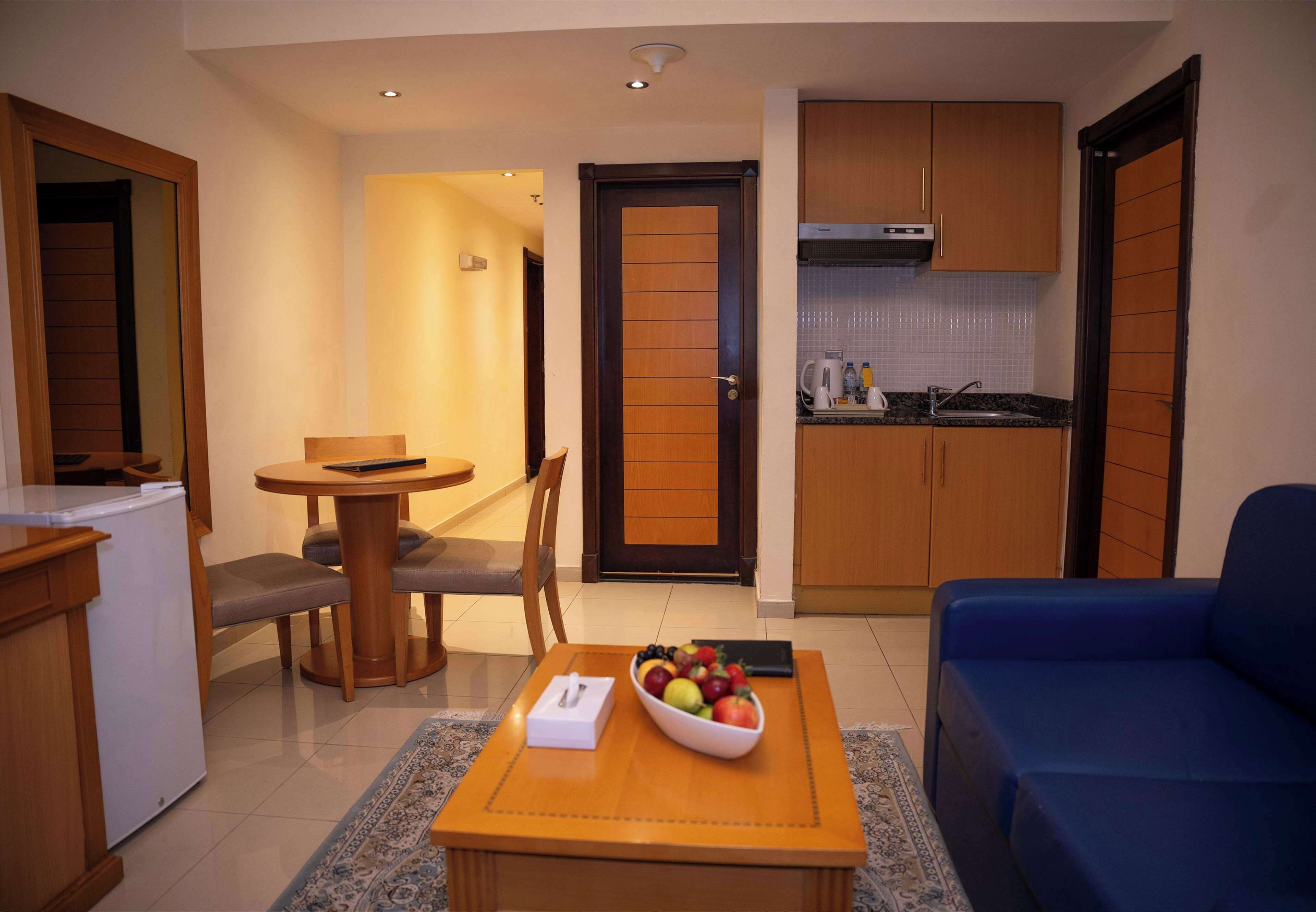 A compact living space with a dining area, kitchenette, and a blue sofa.