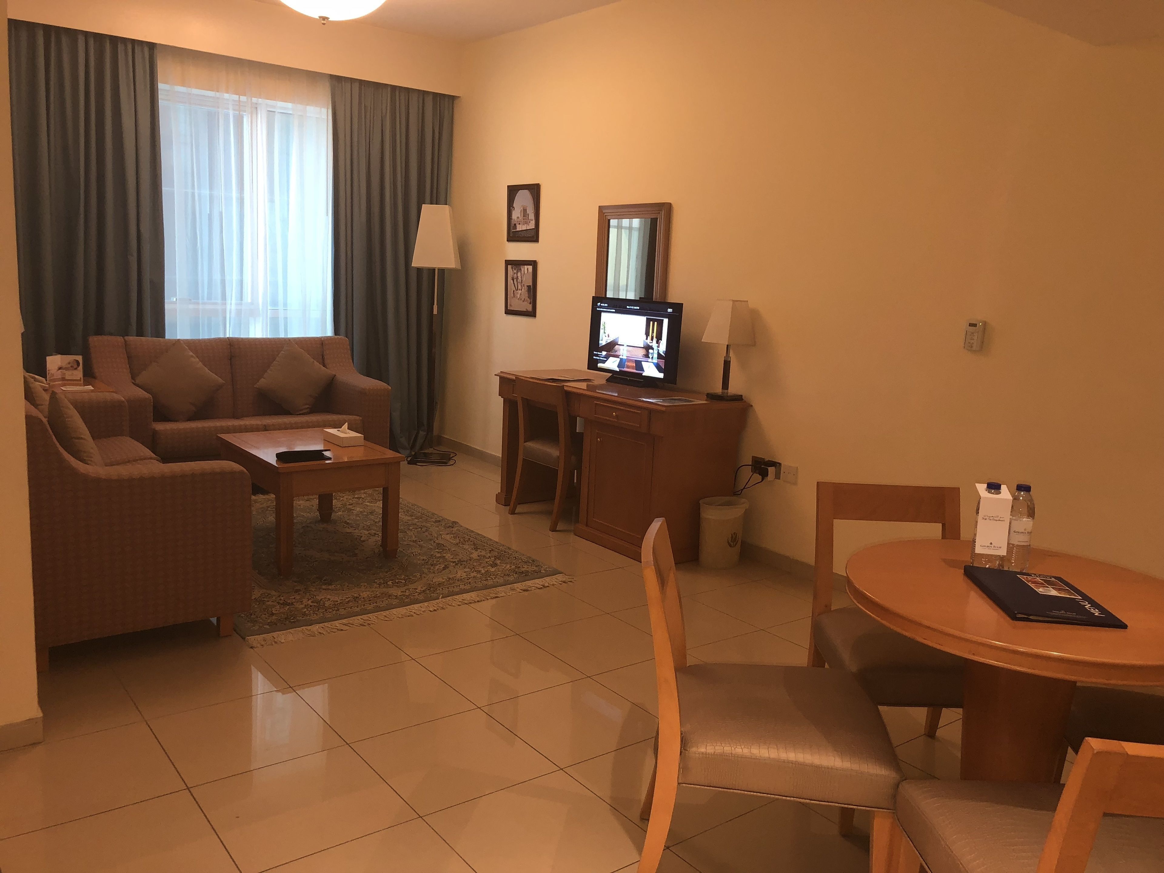 A living room with a sofa, coffee table, TV, and a dining area with a table and chairs.