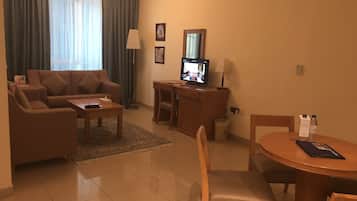A living room with a sofa, coffee table, TV, and a dining area with a table and chairs.